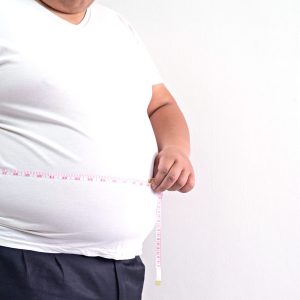 fat man check out his body fat with measuring tape on white background
